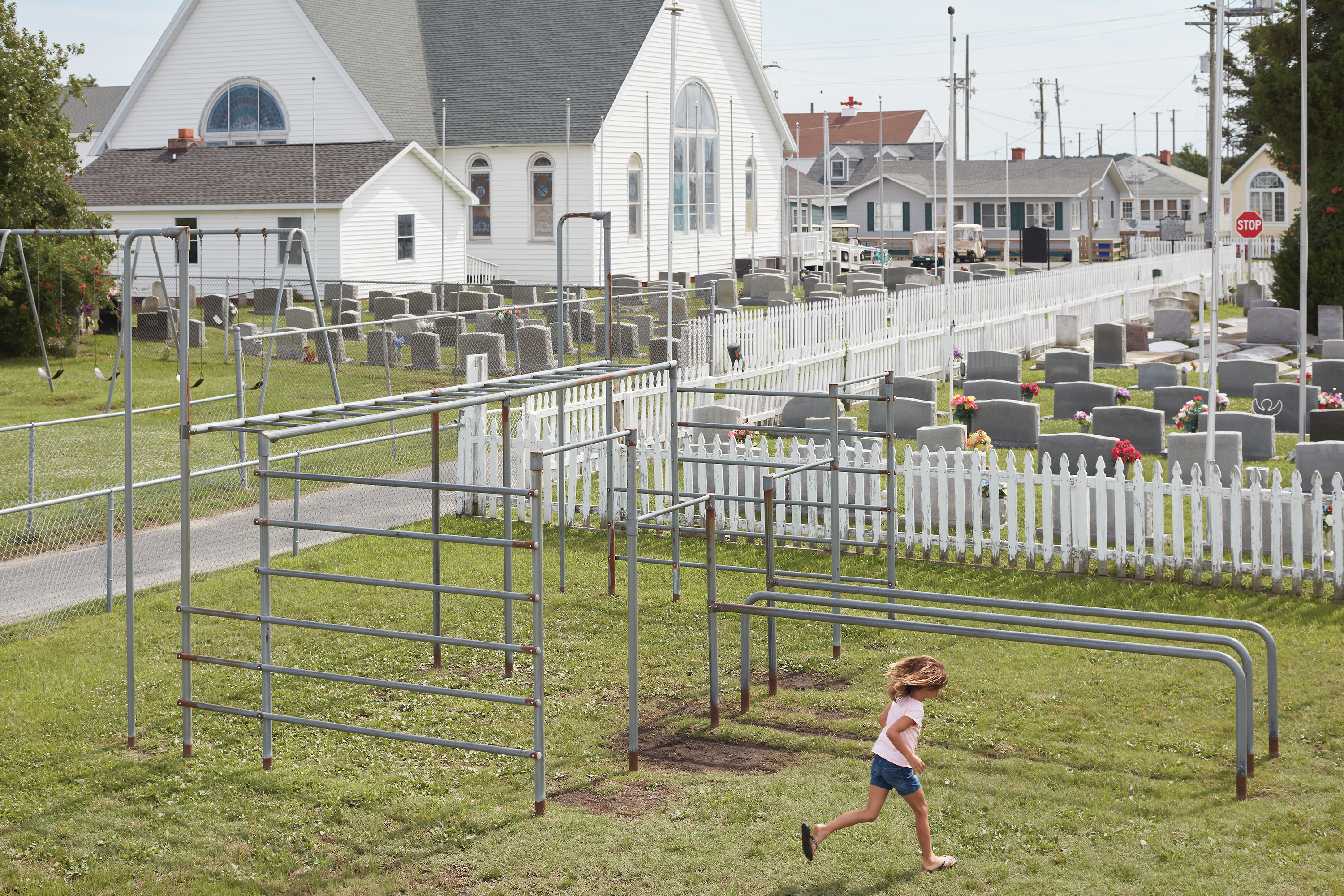 Jordan Daley stretches her legs in Tangier Island's public playground. During high tide, standing water pools beneath the jungle gym.