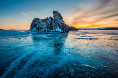 Siberia, Russia: A winter sunset near Ogoy Island on frozen Lake Baikal. With few passable roads, locals drive cars, jeeps, and even cargo lorries over the ice to shorten their journeys.