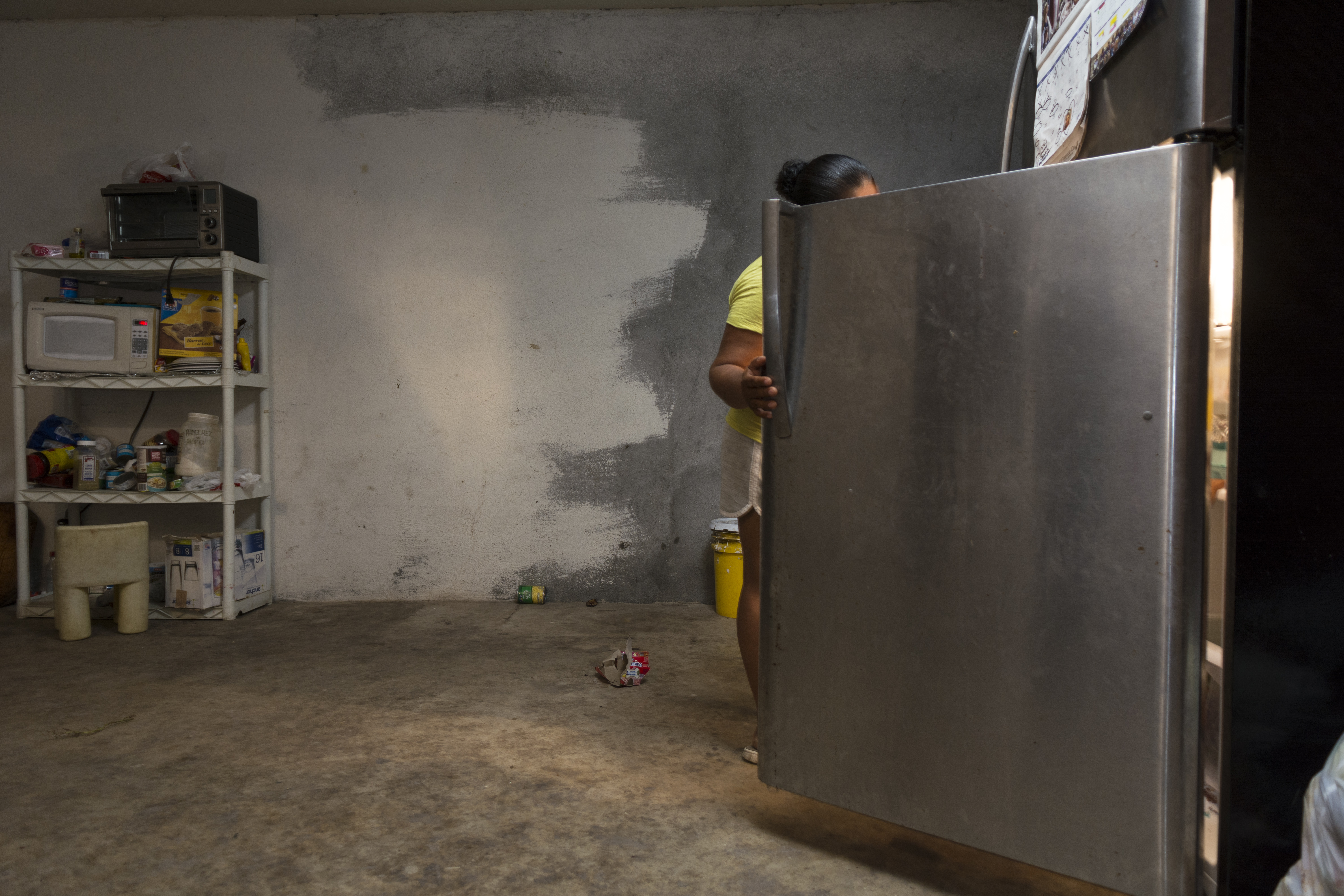 Berenise's mother, Mireya, checks what's in the family's refrigerator.