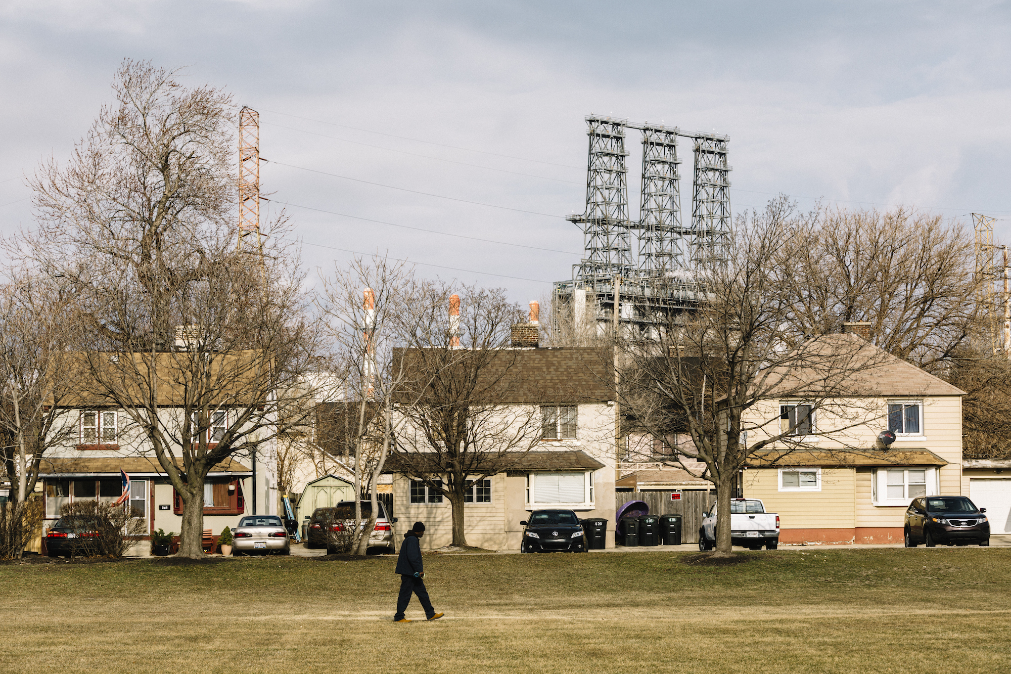 A man walks across a green space in Marktown, a historic district of East Chicago. The area is surrounded by heavy industry, including a BP tar sands refinery.